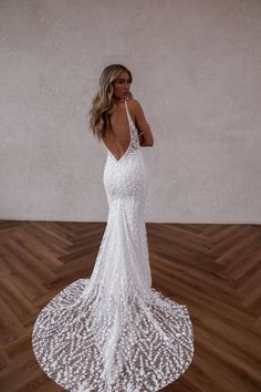 a woman in a white wedding dress standing on a wooden floor with her back to the camera