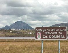 a welcome sign in front of some mountains