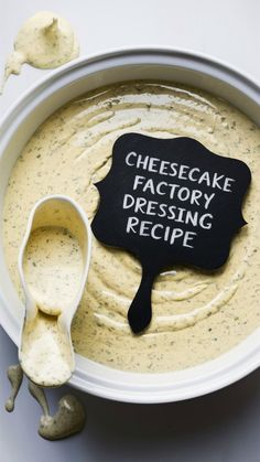 a white bowl filled with cheesecake dressing and a black sign that says cheesecake factory dressing recipe