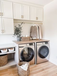 a washer and dryer in a laundry room with white cabinets on the wall