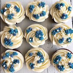 twelve cupcakes with white frosting and blue flowers on them are arranged in a circle