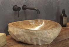 a stone bowl sink sitting on top of a wooden counter next to a soap dispenser