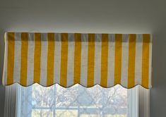 a yellow and white striped window valance hanging on the side of a window sill