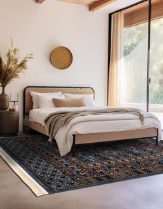 a large bed sitting on top of a rug in a bedroom next to a window