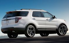 the white ford explorer is driving down the road