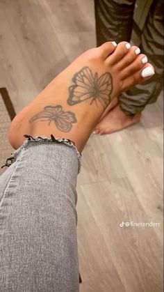 a woman's foot with a butterfly tattoo on her left leg and right hand