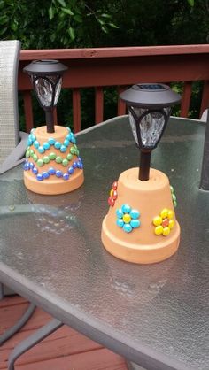 three small lights are sitting on top of a metal table with trees in the background