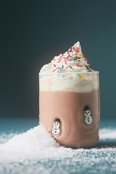 a cup filled with whipped cream and sprinkles sitting on top of a table