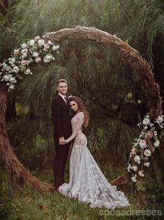 a man and woman standing in front of a circular wooden arch with flowers on it