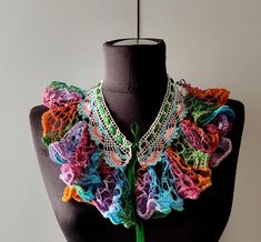 a mannequin wearing a multicolored crocheted scarf on it's neck