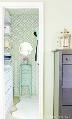 an open closet door shows a dresser, mirror and other items in the room with green wallpaper