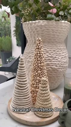 two white vases sitting on top of a table next to each other with plants in them