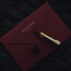 a red envelope with a gold pen on it and the word gucci written in cursive