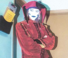 a mannequin wearing a red jacket and hat standing in front of a blue wall