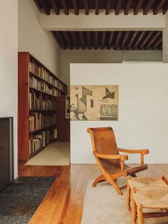 a wooden chair sitting in front of a fire place next to a book shelf filled with books