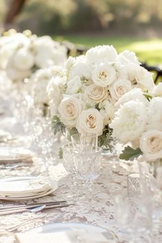 the table is set with white flowers and place settings