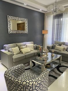 a living room filled with furniture and a chandelier above a glass top coffee table