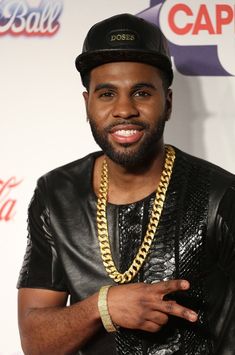 a man with a beard wearing a black hat and leather jacket smiling at the camera