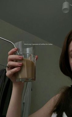 a woman holding up a glass of chocolate milkshake in front of her face