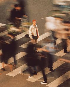 a blurry image of a man holding a skateboard in the middle of a crosswalk