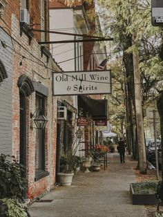 an old mill wine and spirits sign hanging from the side of a building next to a sidewalk