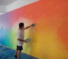 a man is painting a rainbow colored wall