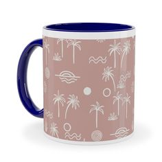 a pink and blue coffee mug with palm trees on the side, in front of a white background