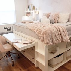 a white bed sitting next to a desk with a laptop computer on top of it