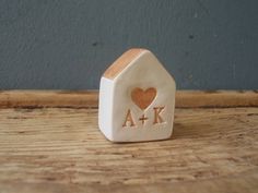 a small wooden house with a heart and initials on the front is sitting on a table