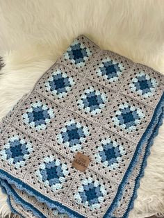 a blue and gray crocheted blanket sitting on top of a white furnishing