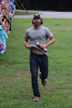 a man running with a frisbee in his hand while people watch from the sidelines