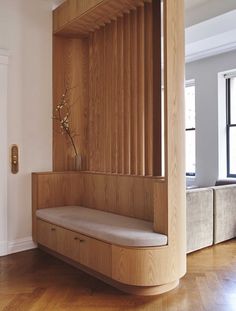 a wooden bench sitting on top of a hard wood floor next to a white wall