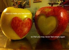 two apples with hearts carved into them sitting on a table