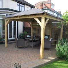 a wooden gazebo sitting on top of a patio next to a lush green yard