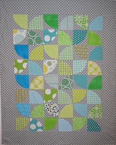 a quilted wall hanging on the side of a white wall with green and blue designs