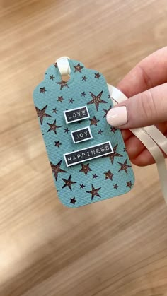 a hand holding a tag that says love joy and happiness with star designs on it