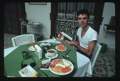 a man sitting at a table with plates of food in front of him and an open book on the table