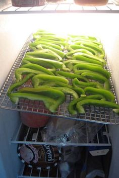 green peppers are on the rack in an open refrigerator, ready to be cooked and put into the freezer