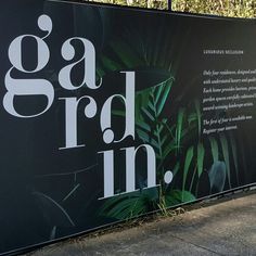 a black and white advertisement for gard in on the side of a building with trees behind it