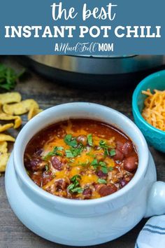 the best instant pot chili in a bowl with cheese and tortilla chips next to it