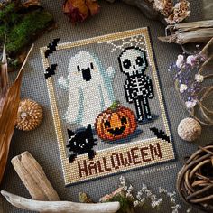 a cross stitch halloween scene with pumpkins and ghost