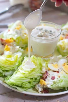 someone pouring dressing onto a plate of lettuce