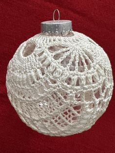 a white crocheted ornament hanging on a red background