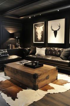 a living room with leather couches and cow hide rugs on the floor in front of two framed deer heads