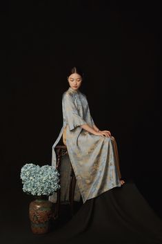 a woman sitting on top of a chair next to a vase with flowers in it