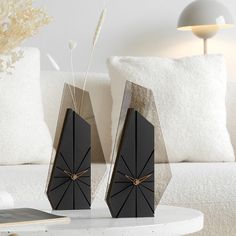 two black clocks sitting on top of a table next to a white couch in a living room