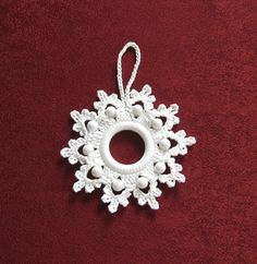 a white snowflake ornament hanging on a red blanket with a string