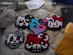 four hello kitty iron - on patches sitting on top of a bed next to a laptop computer