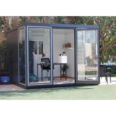 a small office in the middle of a yard with an open door and glass walls