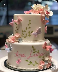 a three tiered cake decorated with flowers and butterflies